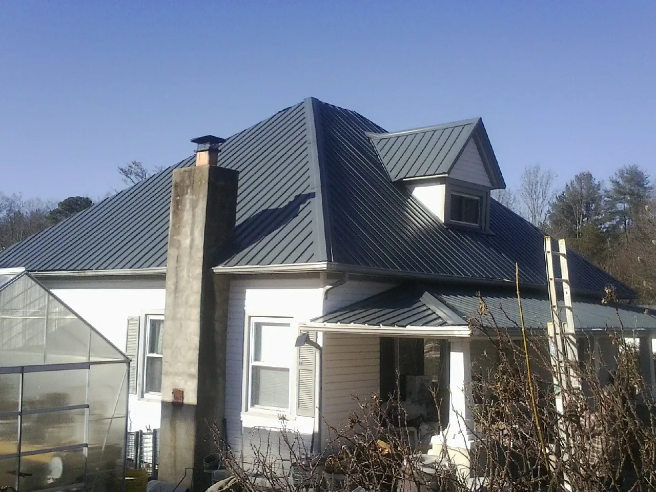 Dark blue standing seam metal roof on a white farmhouse with dormer — Slate & Tile Roof Repair by Roofing Brothers in Crown Point