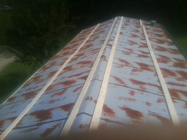 Rusted metal roof panels with new wood purlins before replacement — Storm Damage Roof Repair in Crown Point by Roofing Brothers