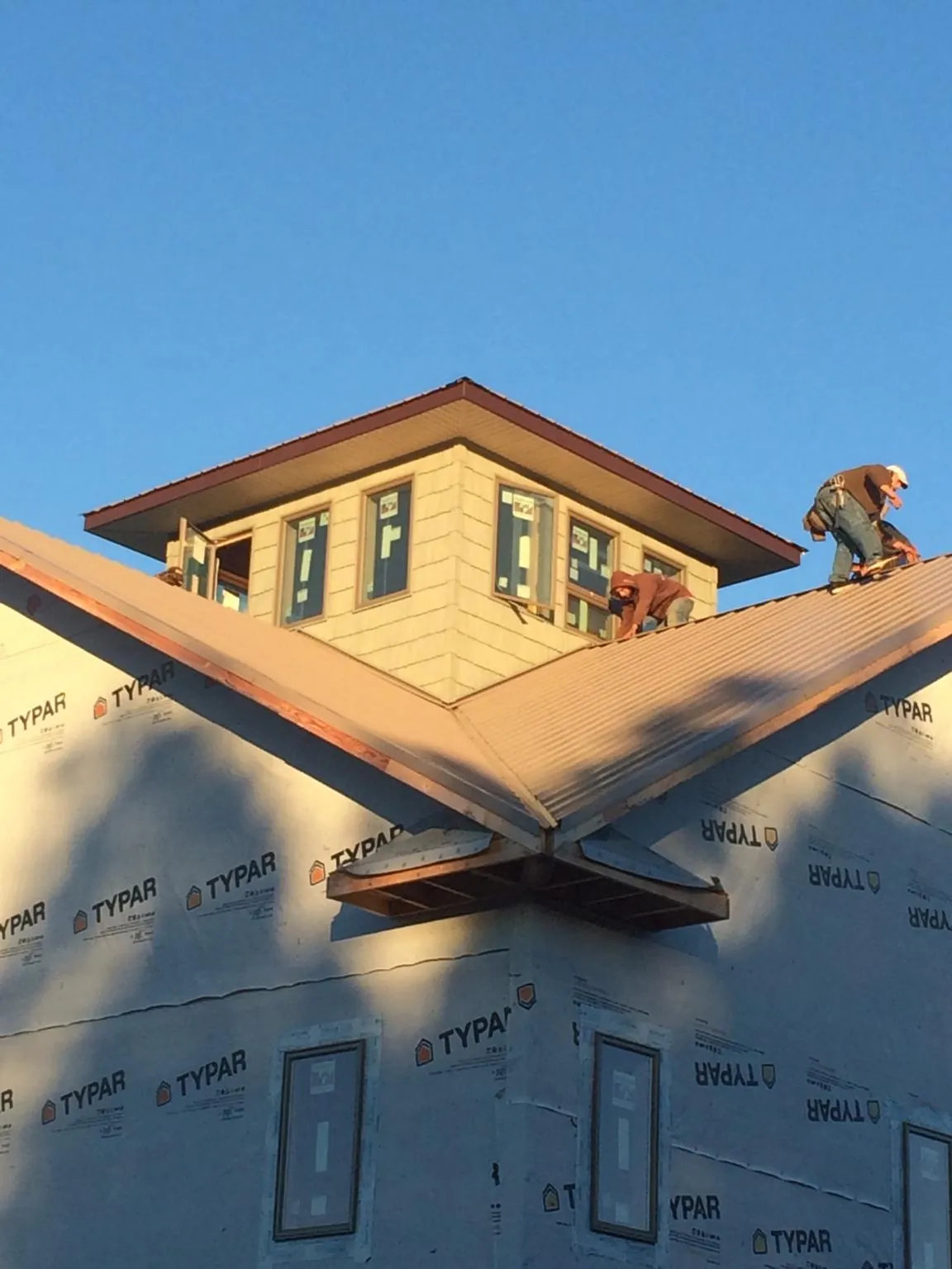 Roofers working around a rooftop cupola on a new metal roof at sunset — Roof Waterproofing in Crown Point by Roofing Brothers